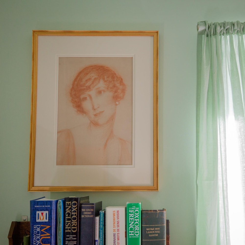 Un tableau dessiné au fusain d'Agnès Slayden est accroché au mur, au-dessus d'une étagère de livres
