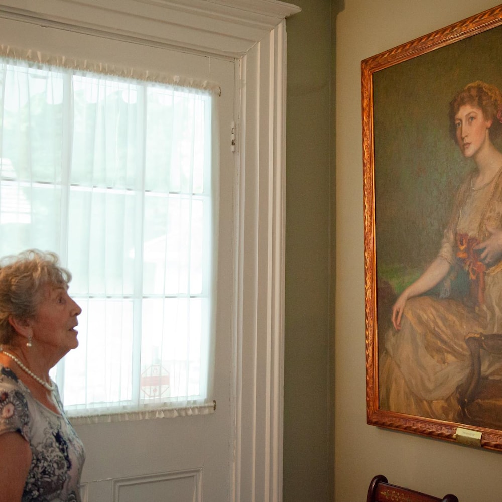 Rollande Marchand, à gauche, regarde le portrait peint de son ancienne patronne, qui est accroché au mur