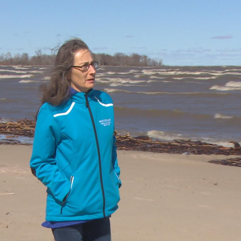 Dorothy Monkman marche sur une plage par une journée de grand vent le long du lac Manitoban.