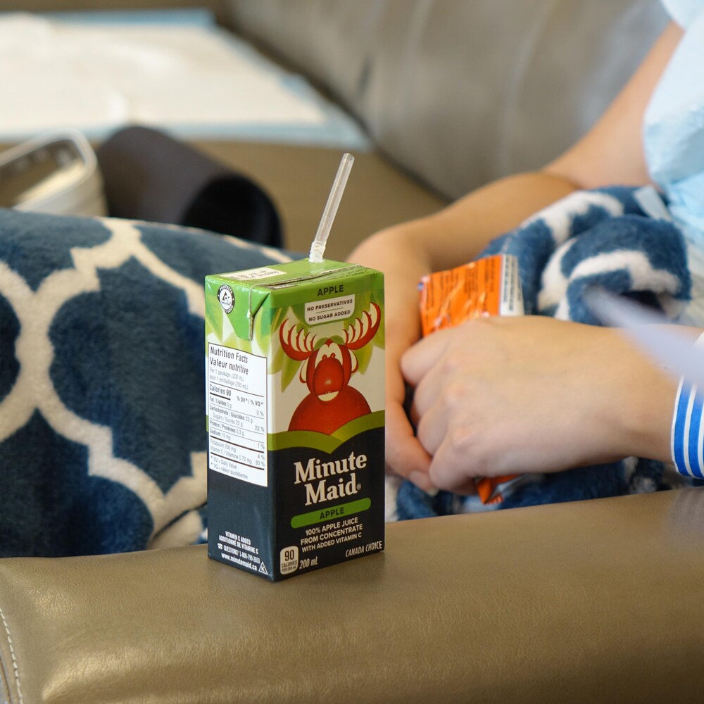 Une femme installée sur un sofa avec une boîte à jus.