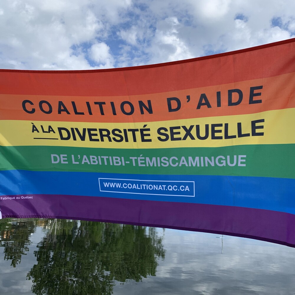 Martin et Sébastien tiennent le drapeau de la Coalition d'aide à la diversité sexuelle de l'Abitibi-Témiscamingue.