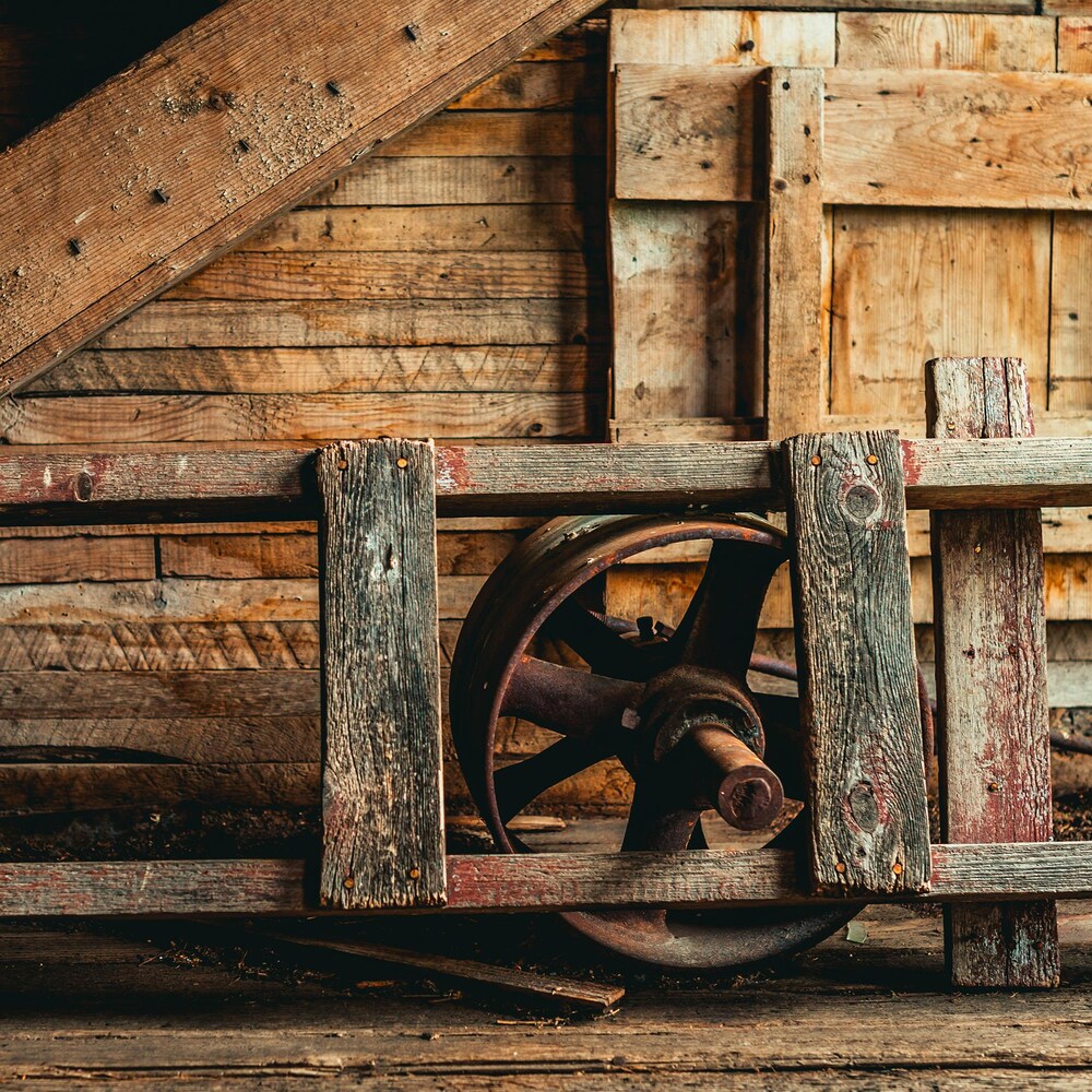 Une échelle en bois, avec une vieille roue en métal rouillé devant un mur en bois, à Barnsley au Manitoba, début juin 2022.