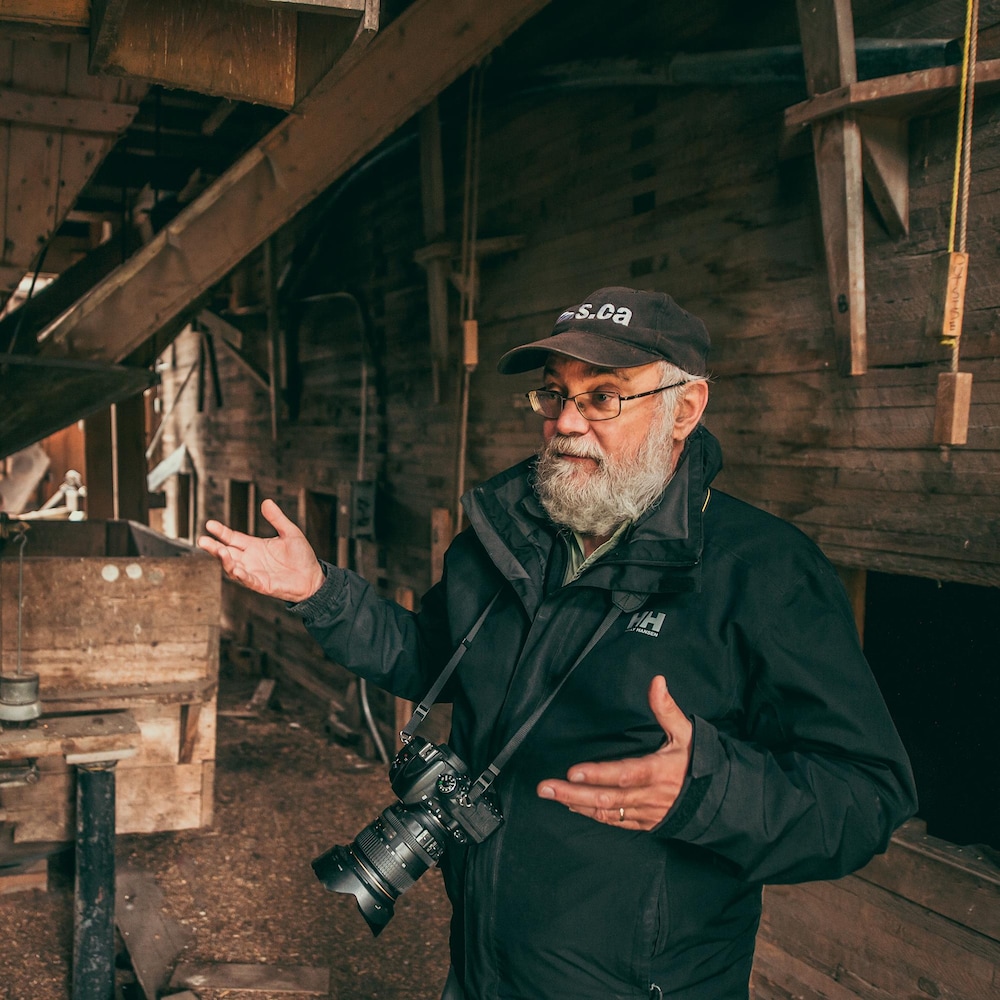 Gordon Goldsborough est dans un très vieil élévateur à grains tout en bois, son appareil photo autour du coup, à Barnsley au Manitoba, début juin 2022.