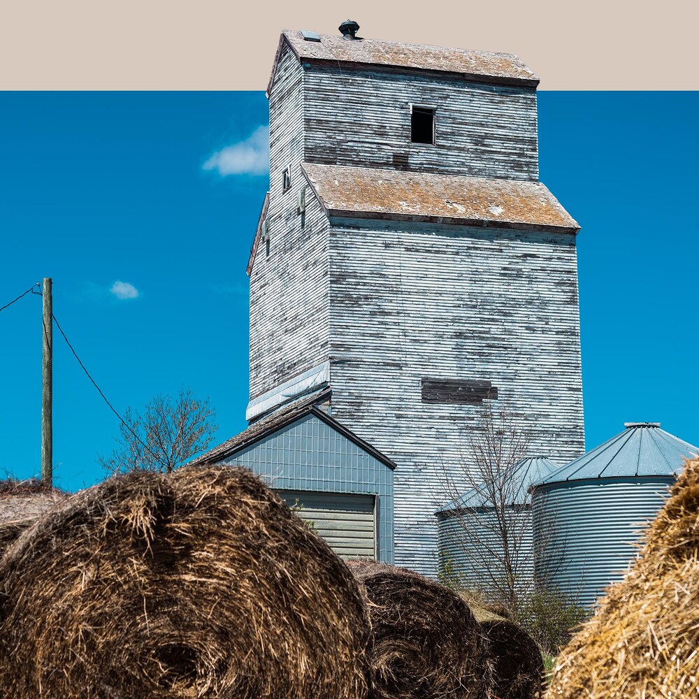 Un ancien silo à grain avec de grosses bottes de paille devant, à McConnell au Manitoba, début mai 2022. 