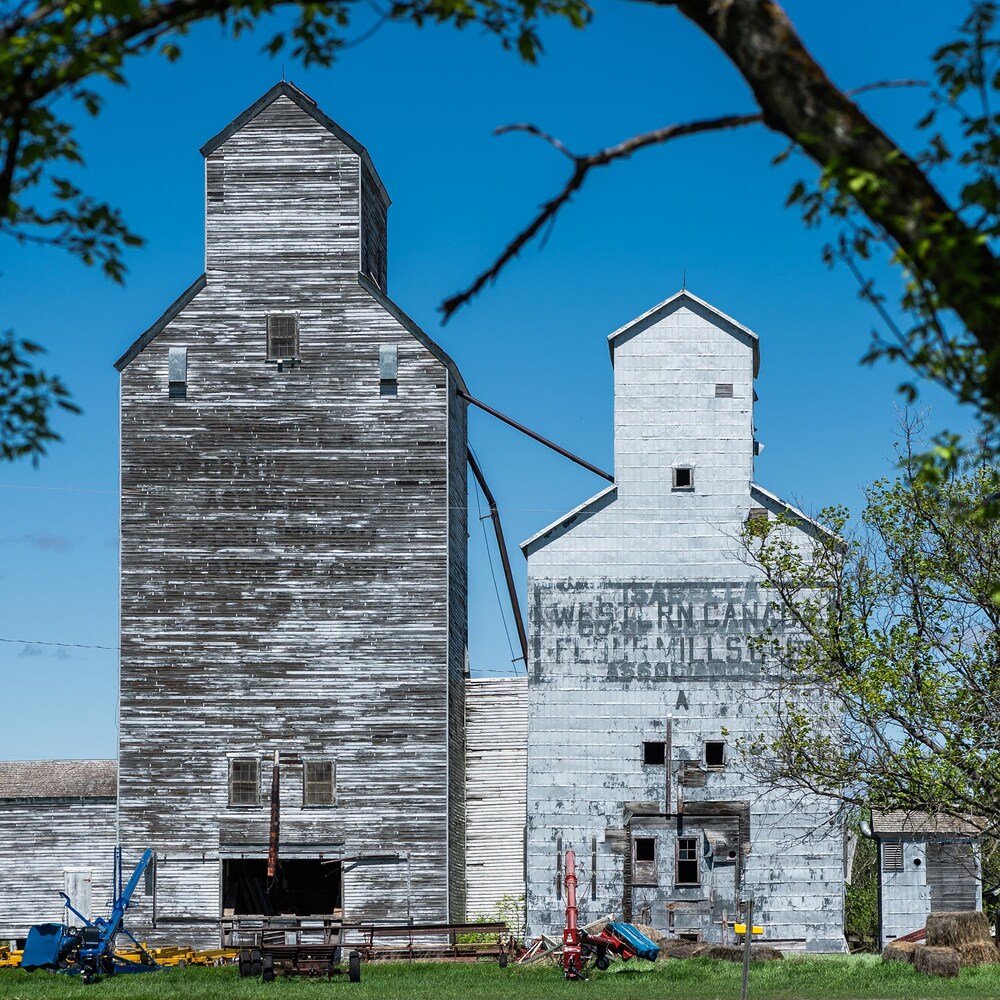 Un vieux silo à grain, avec des machines agricoles, à Isabella au Manitoba, début mai 2022.