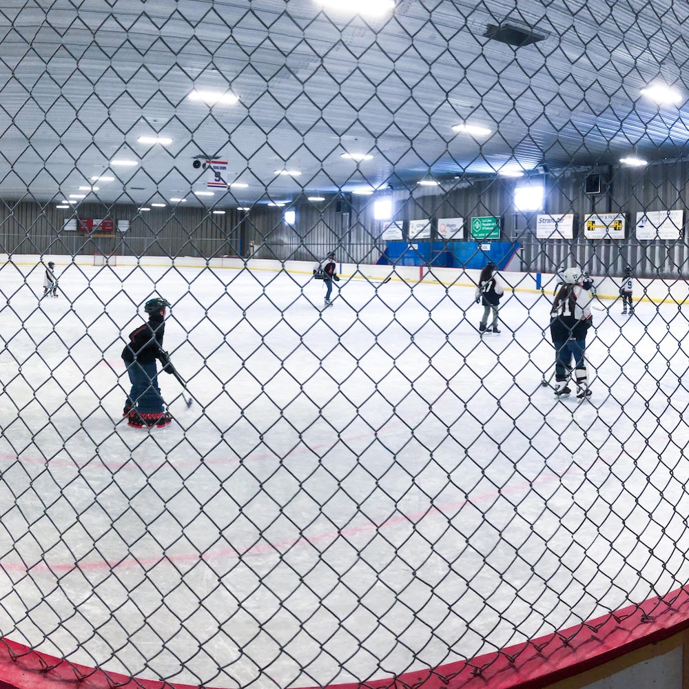 Des élèves jouent au hockey sur la patinoire.