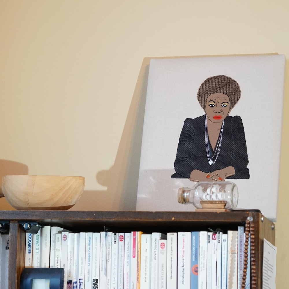 Sur une étagère est disposé une toile d'art contemporain qui affiche un portrait de la célèbre Miriam Makeba et deux bols artisanaux en bois.