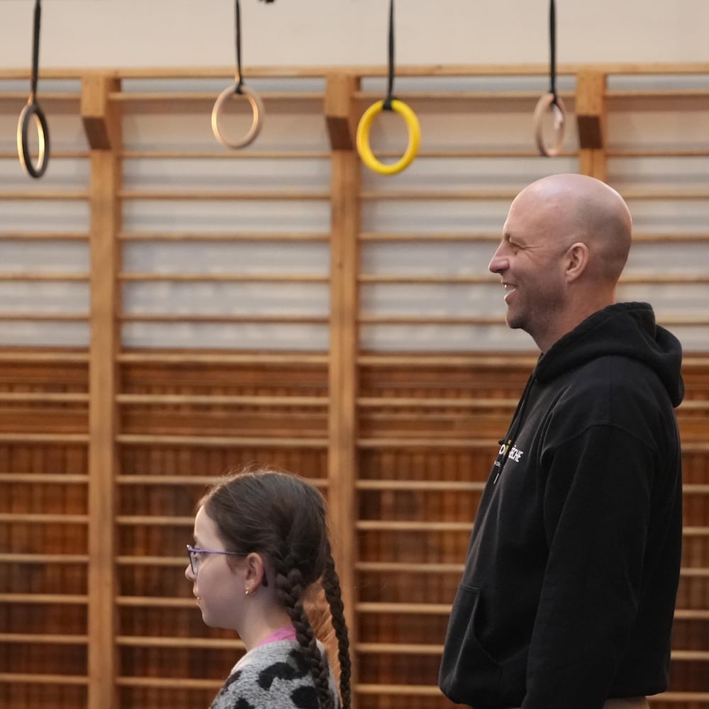 Un homme et une jeune fille sont dans un atelier devant des anneaux de cirque. 