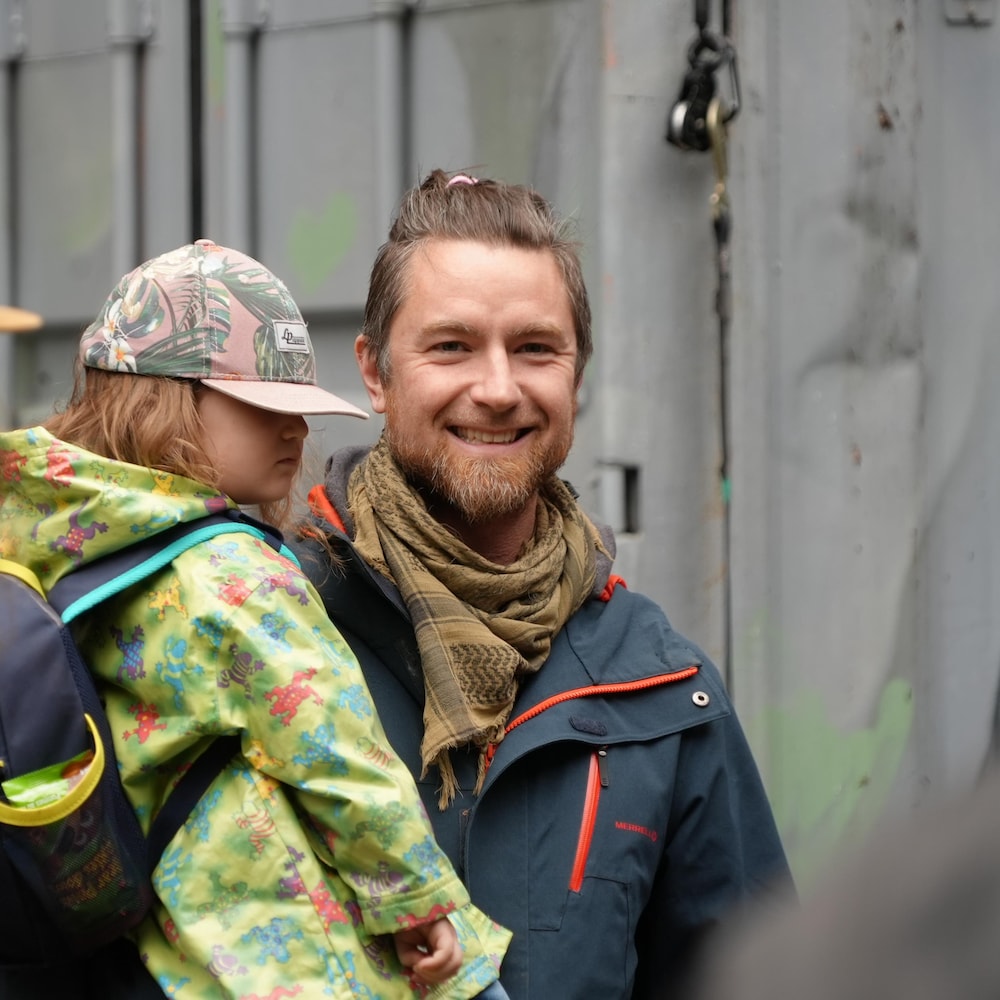 Un papa pose en souriant avec sa jeune fille dans ses bras.