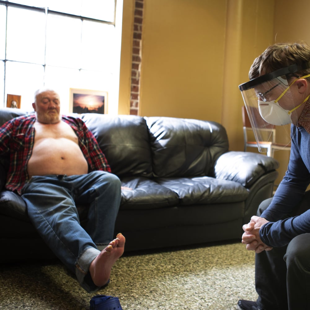 Dr Conway, portant un masque, examine le pied d'un patient.