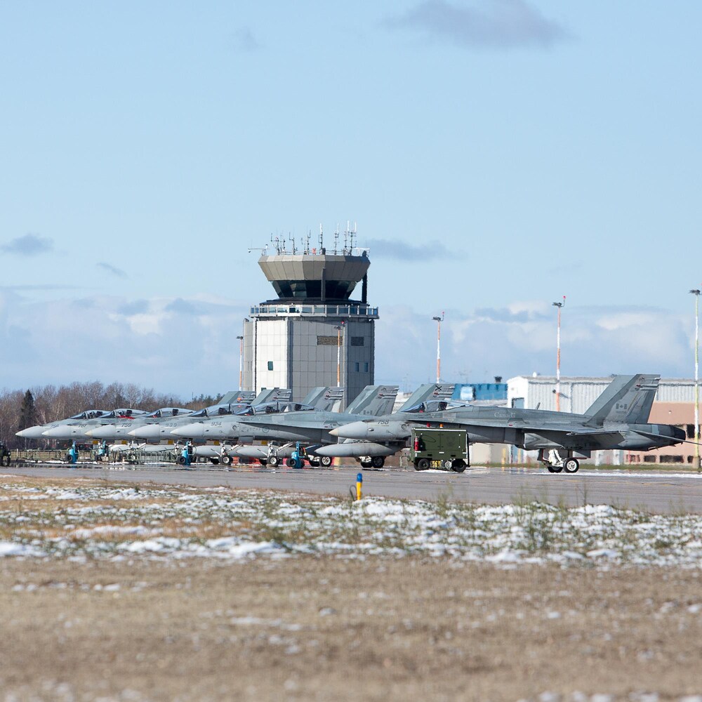 Des CF-18 stationnés devant la tour de contrôle de la base des Forces canadiennes de Bagotville.