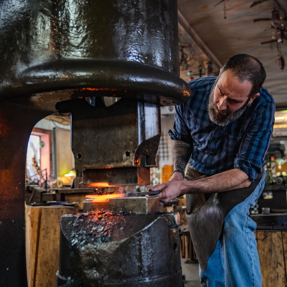 Dans sa forge, Romain Francès utilise un marteau-pilon pour donner une forme au métal chaud.