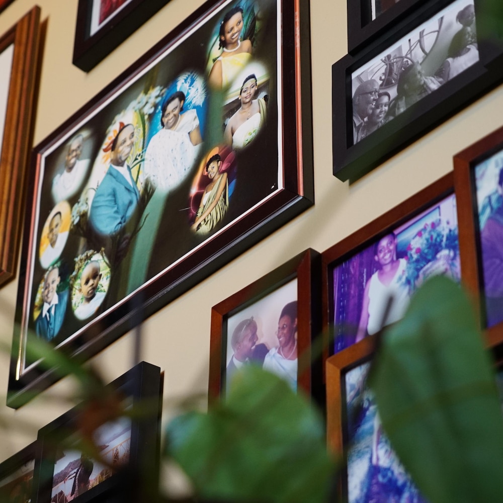De multiples cadres avec des photos de famille de Jeanne-Marie Rugira sont accrochés au mur de sa maison. 
