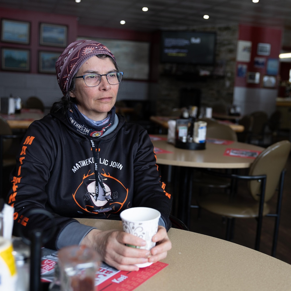 Chantale Dufour est assise à la table d'un restaurant café à la main et pensive. 