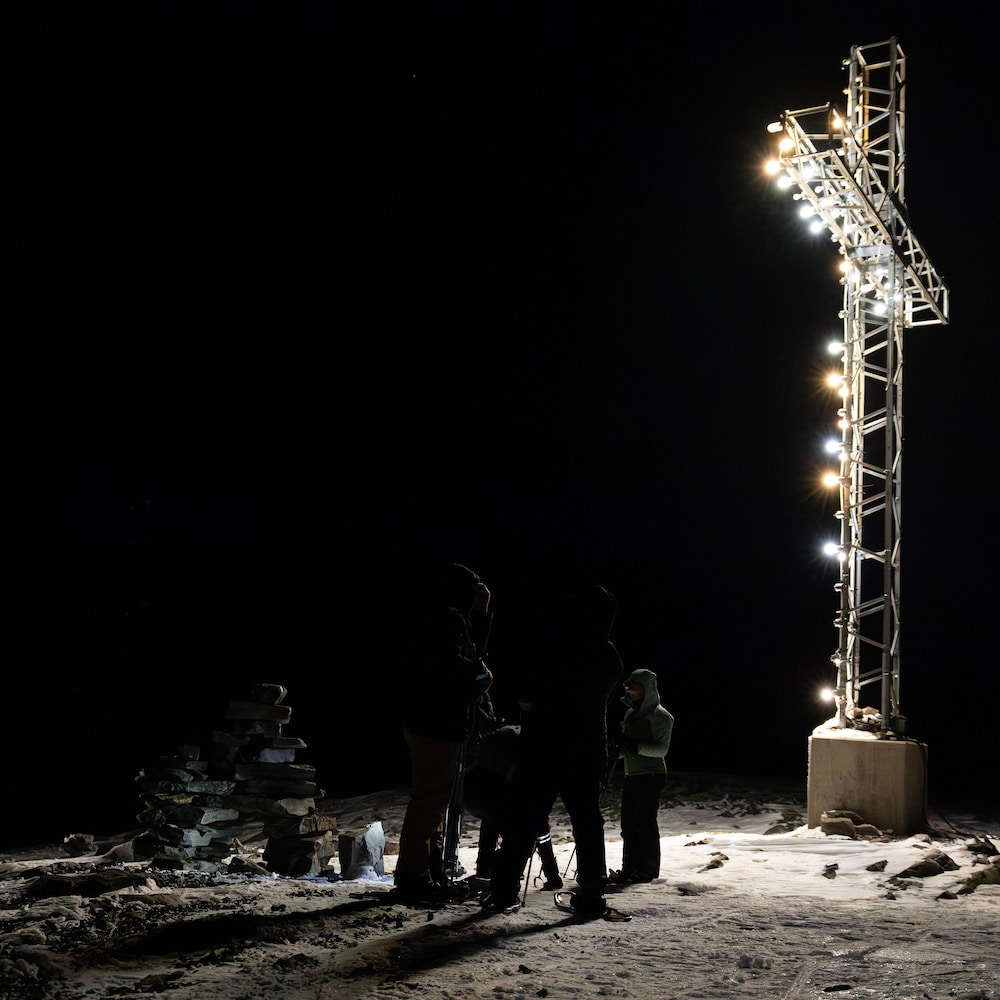 Un groupe de marcheurs sous la croix Knob illuminée, le soir à Schefferville. 