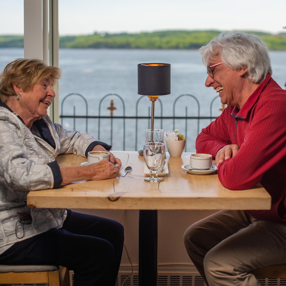 Une femme et un homme sont assis à une table et discute en riant. 