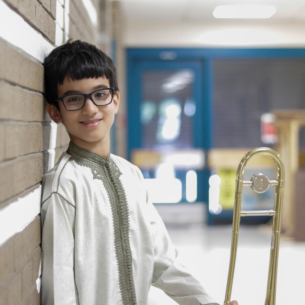 Omar pose avec son trombone dans les corridors de Sistema à Moncton.