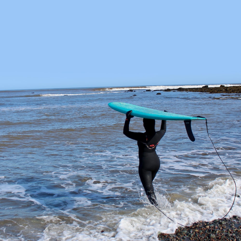Juniper qui transporte sa planche de surf vers l'océan agité.