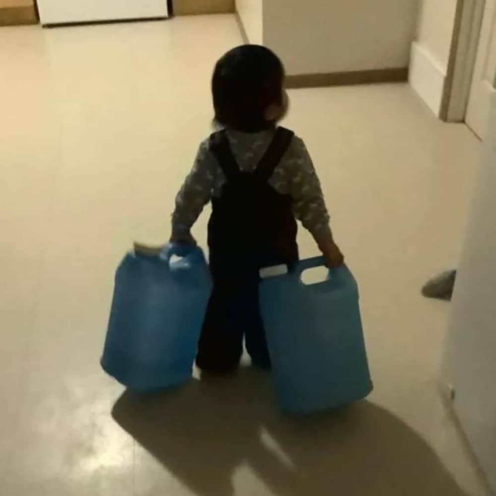 Un enfant transporte des cruches d'eau en bouteille.