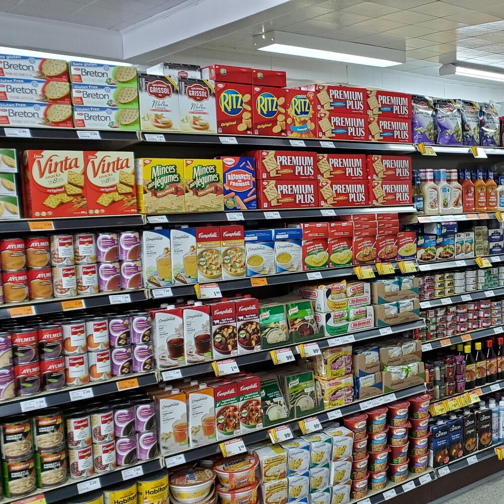 Une allée d'épicerie dont les étagères sont remplies de produits.