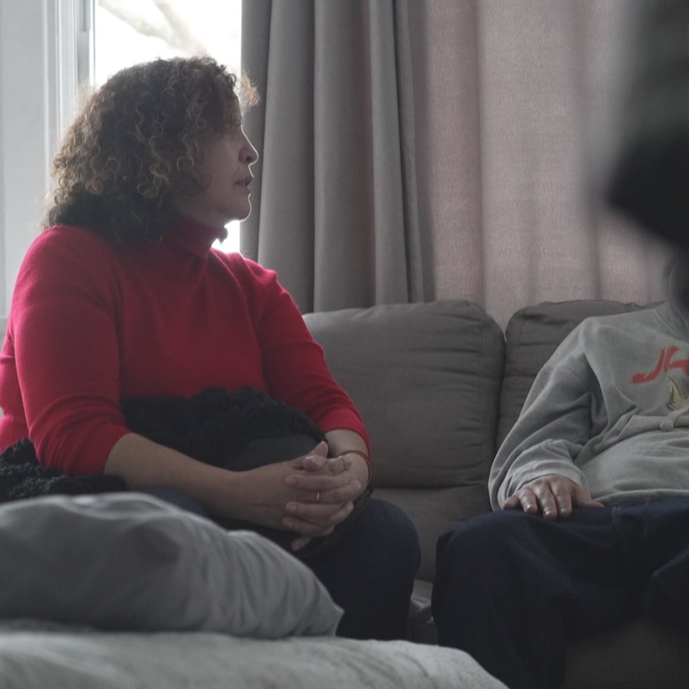 Une femme assise sur un sofa discute avec un jeune homme.