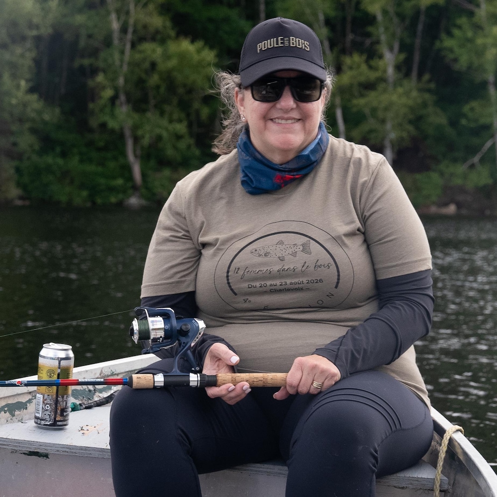 Une femme dans une chaloupe avec une canne à pêche à la main.