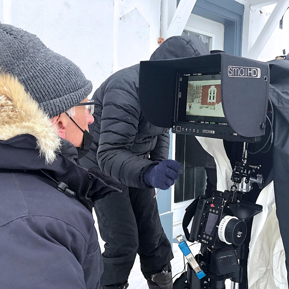 Assis à l’extérieur avec son manteau d’hiver, le réalisateur du film, Bernard Émond, regarde à travers une caméra l’image de la maison de son personnage principal.