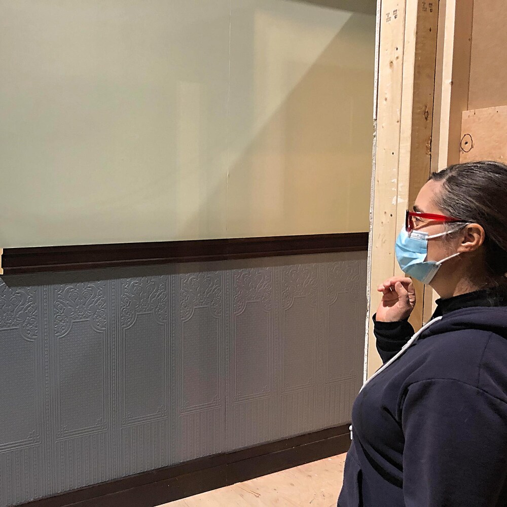 À droite, Caroline Alder regarde devant elle un grand panneau qui deviendra un mur intérieur de la maison en studio.