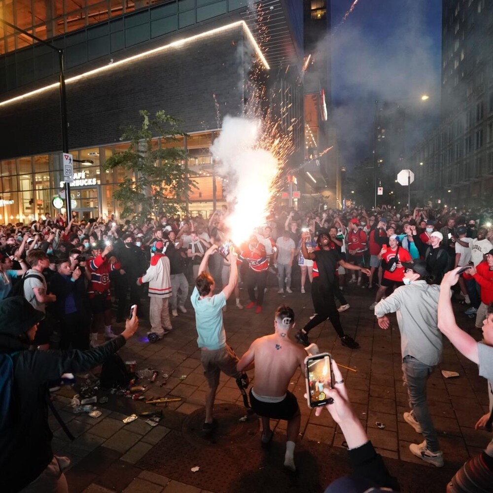 Une foule dispersée autour d'un homme qui tient des feux d'artifice.