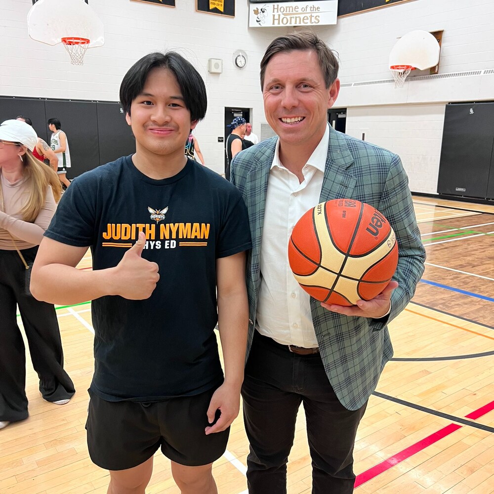 Isang Pilipino at Canadian hawak ang bola ng basketball sa loob ng court.
