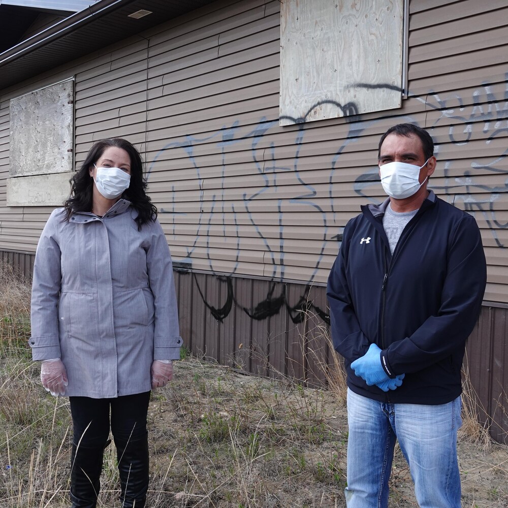 Tanya Fayant et Wayne Daniels devant une bâtisse qui porte des graffiti.