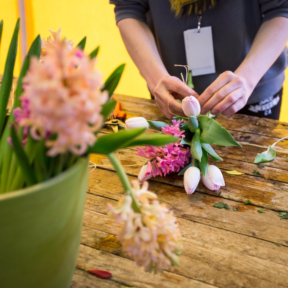 Les mains d'une employée de la fleuriste attachent un bouquet de fleurs.