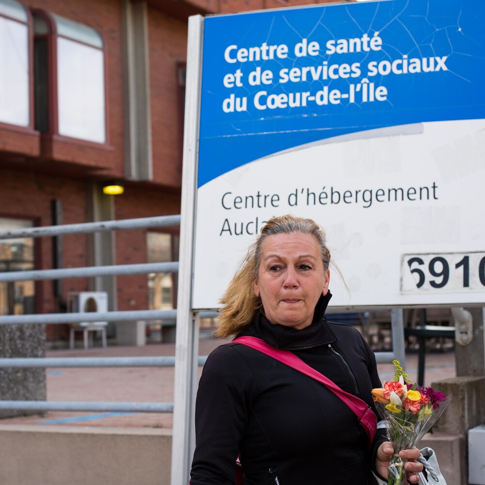 Une employée émue par la présence des bénévoles tient un bouquet en main.