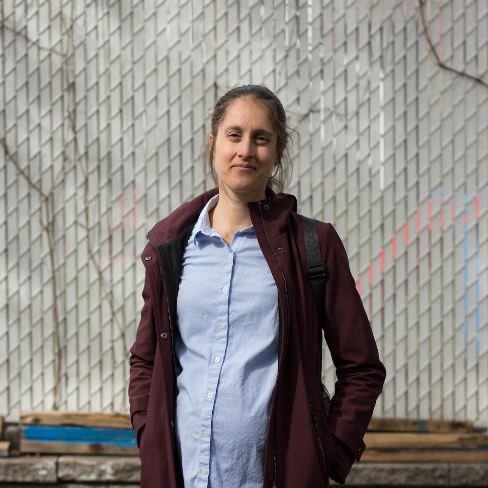 Emily Lavertu pose devant une clôture, dans un quartier de Montréal.