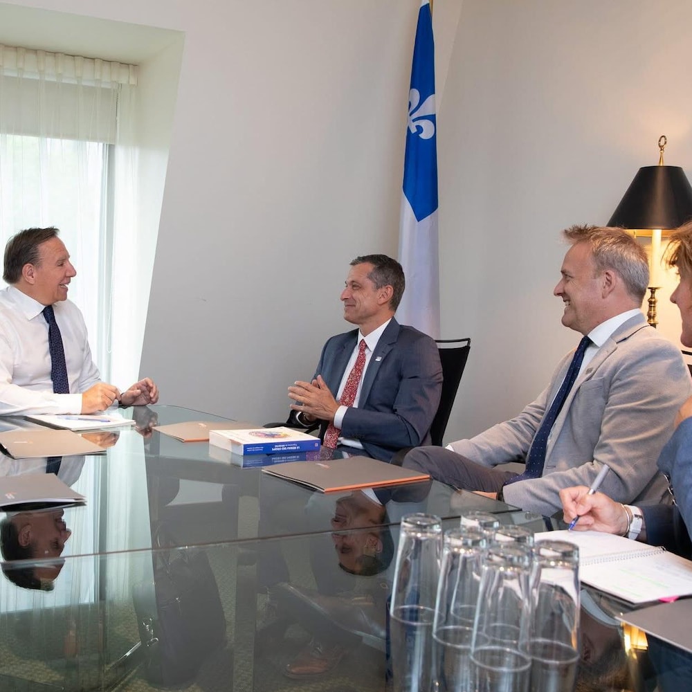 Quatre personnes, dont le premier ministre du Québec, attablées lors d'une rencontre officielle.