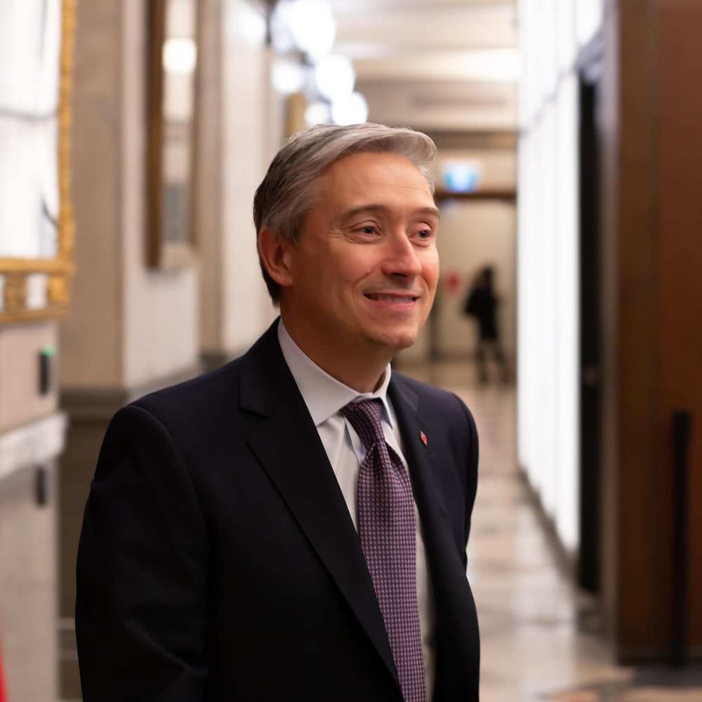 Le député dans un couloir, avec un drapeau canadien, à Ottawa.