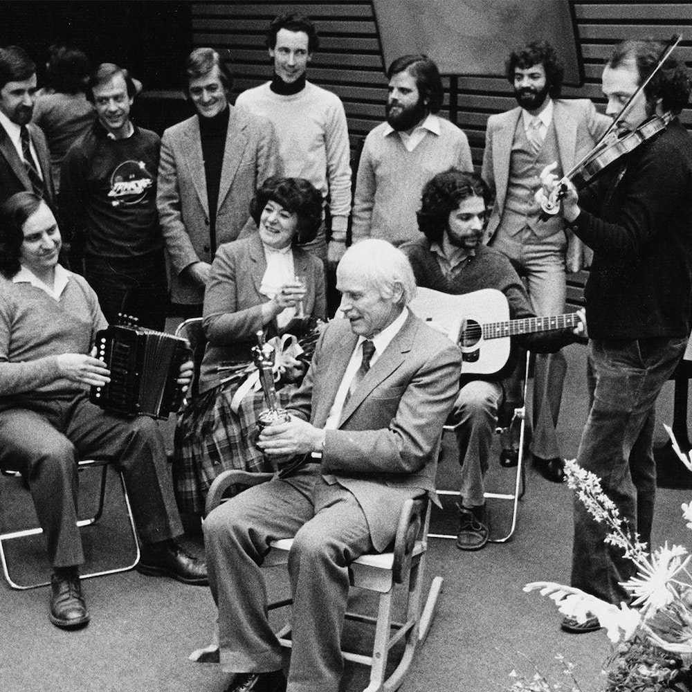 Frédéric Back dans une chaise berçante avec son Oscar. Autour de lui, ses proches et les membres de l'équipe du film « Crac! ».