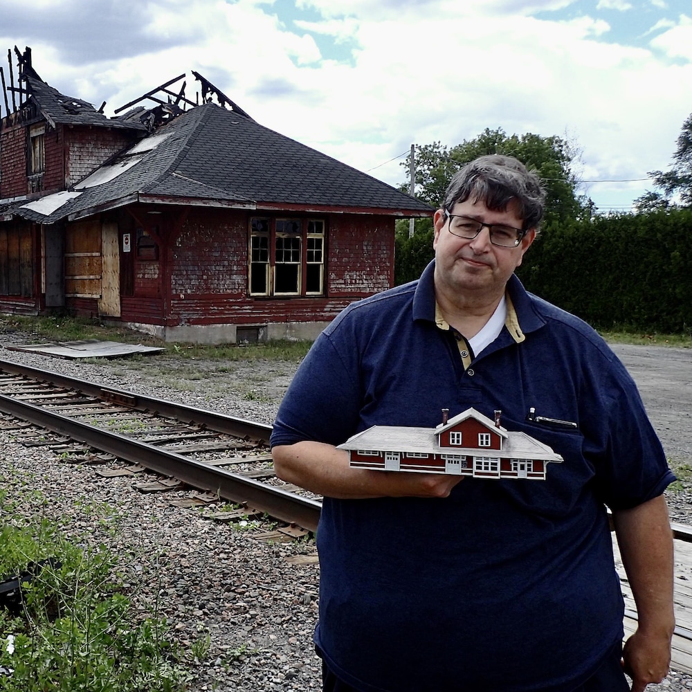 Le maire de L'Épiphanie, Steve Plante, et le président de l'Institut de recherche sur l'histoire des chemins de fer au Québec, Claude Martel, posent devant les ruines de la gare. Claude Martel tient à la main une maquette de la gare qu'il a fabriquée lui-même.  