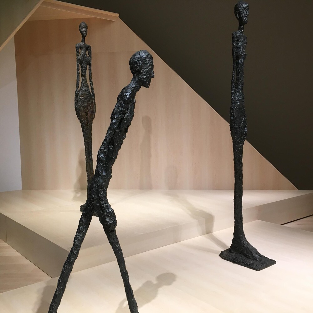 L'homme qui marche de Giacometti, 1960. Il s'agit d'une sculpture monumentale en bronze, On y aperçoit un homme filiforme.