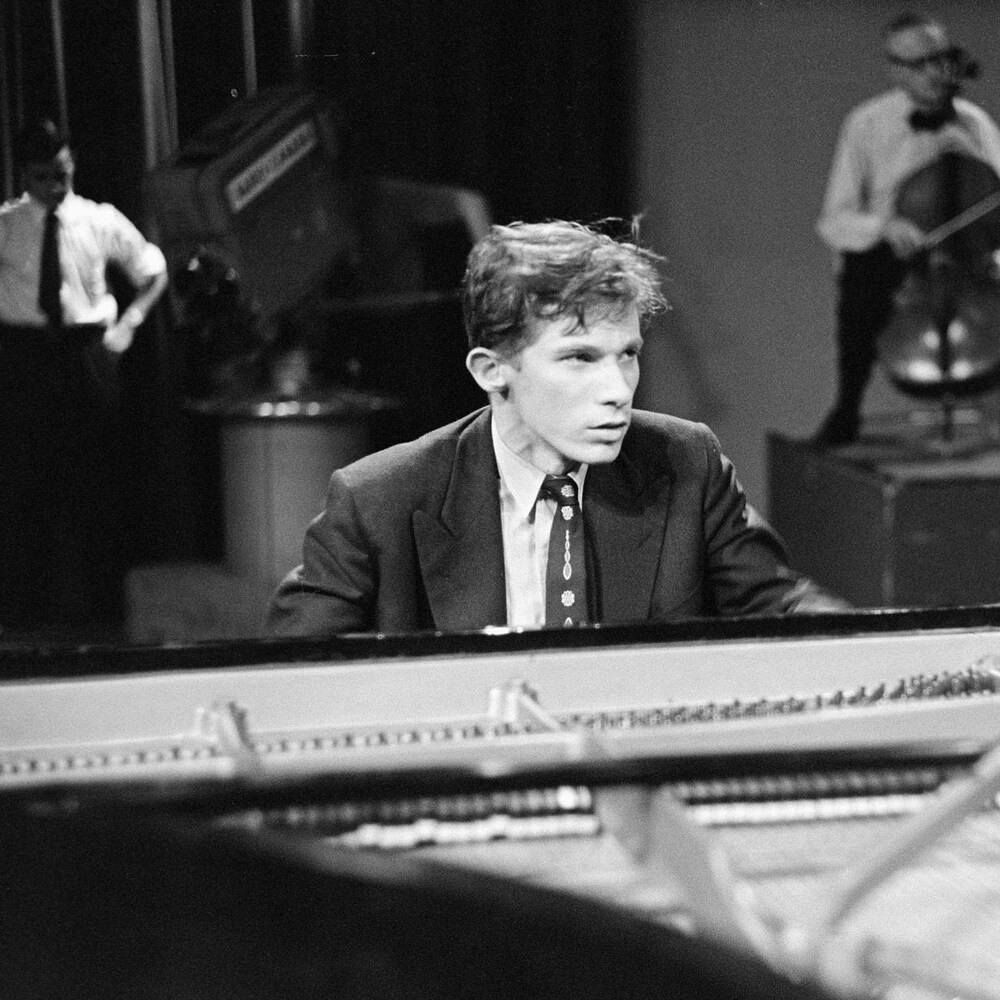Le pianiste Glenn Gould assis au piano, en réflexion, lors d'une performance en studio.
