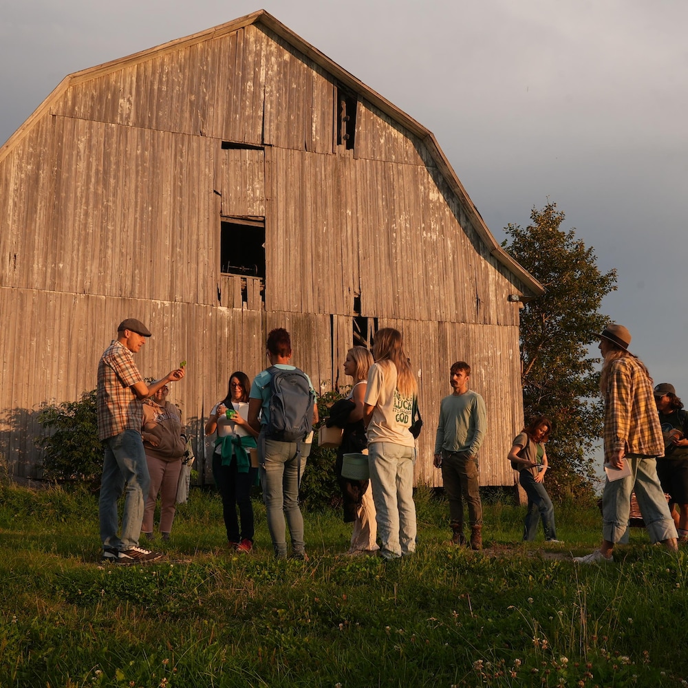 Des personnes discutent en groupe près d'une grange.