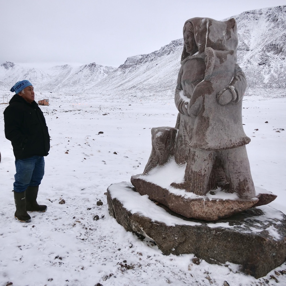 Larry Audlaluk regarde le monument commémoratif qui représente une femme et un enfant enlacés.