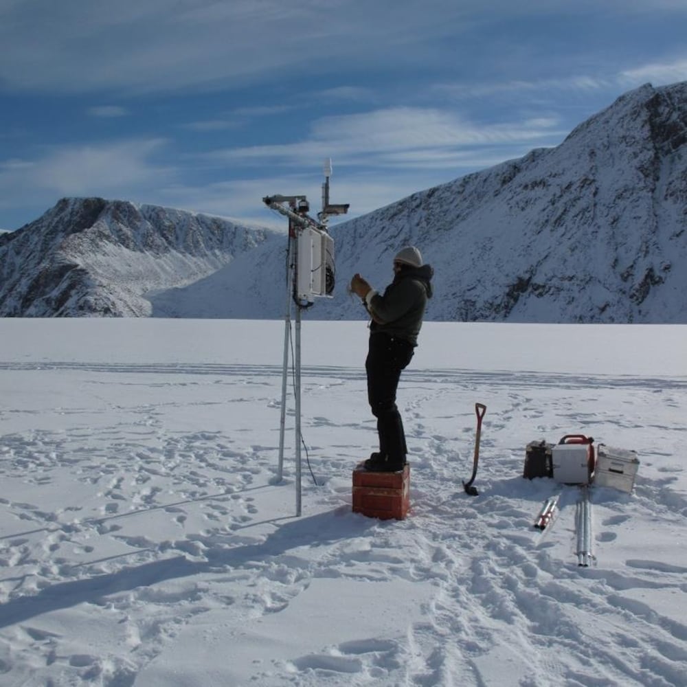 Un chercheur installe un appareil sur la glace gelée recouverte de neige.