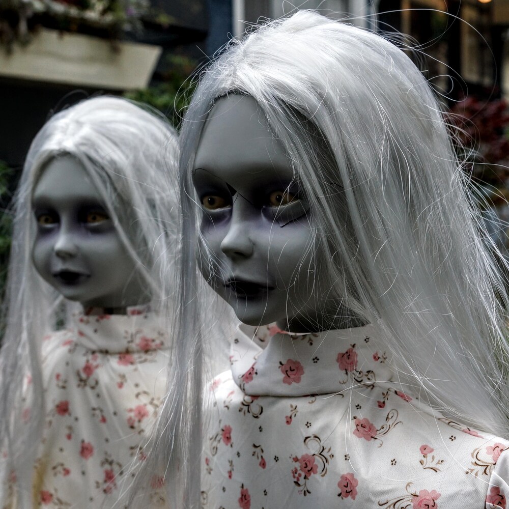 Deux fausses petites filles monstrueuses sont disposées devant une maison pour halloween.