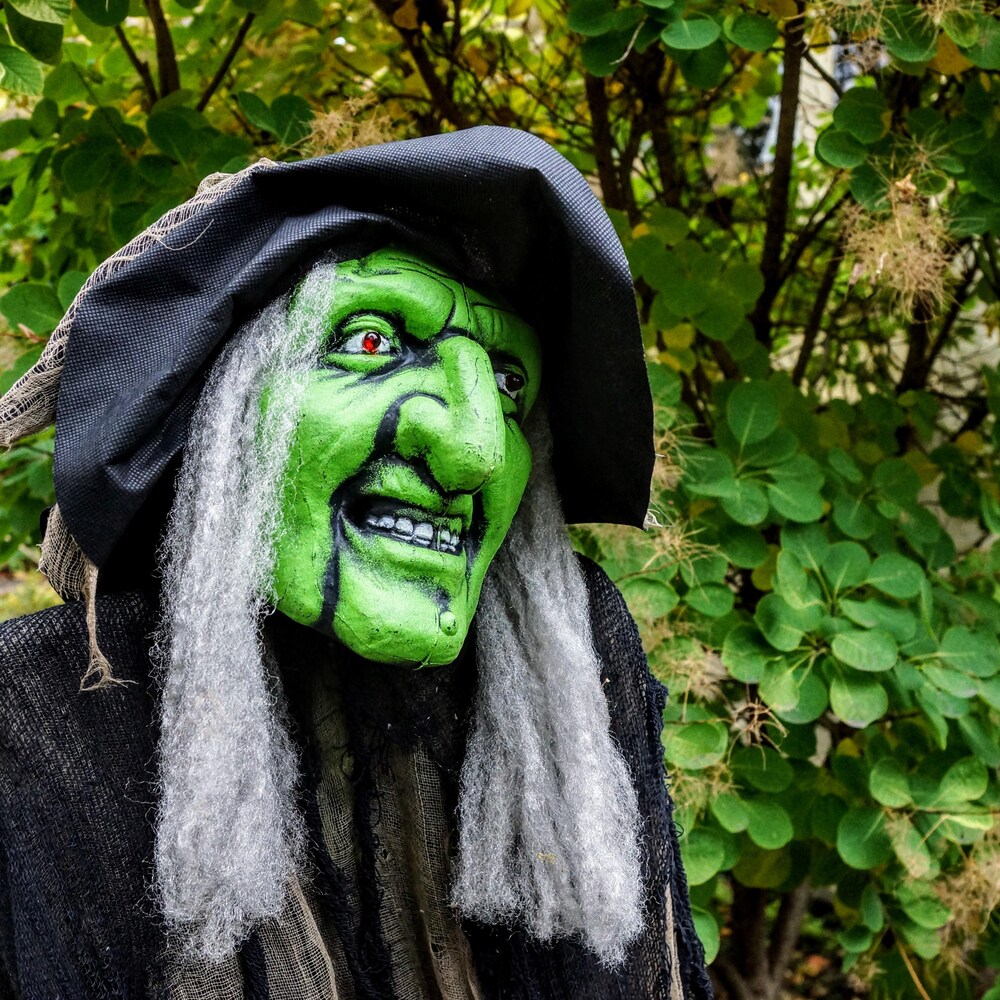 Une reproduction de sorcière est disposée devant une maison.