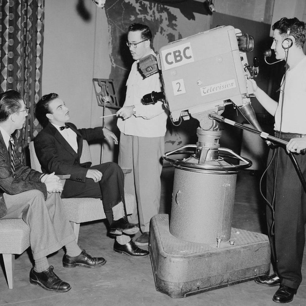 Henri Bergeron, assis devant la caméra aux côtés de l’animateur Bruce Marsh, conversant avec l’équipe de production.