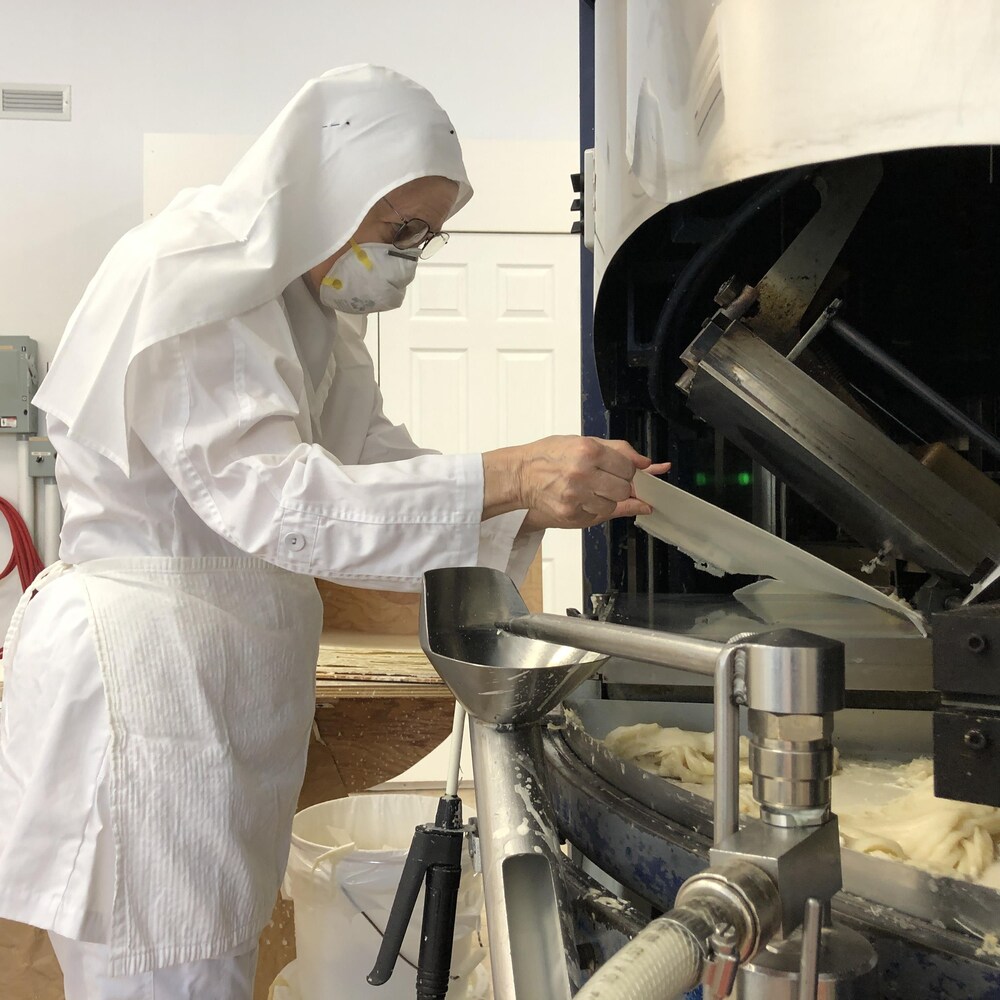 Une religieuse opère une machine pour fabriquer des hosties.