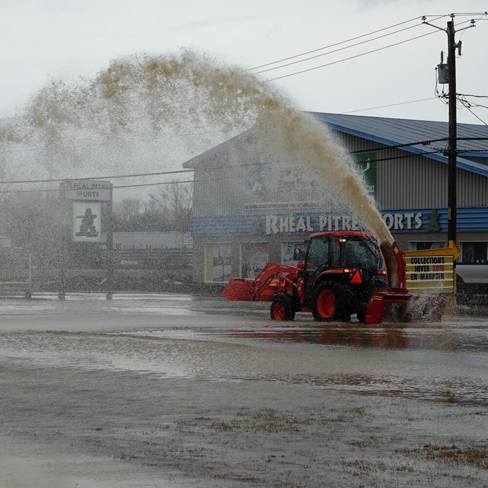 Un tracteur souffle de l'eau à New Richmond, le 2 décembre 2020.