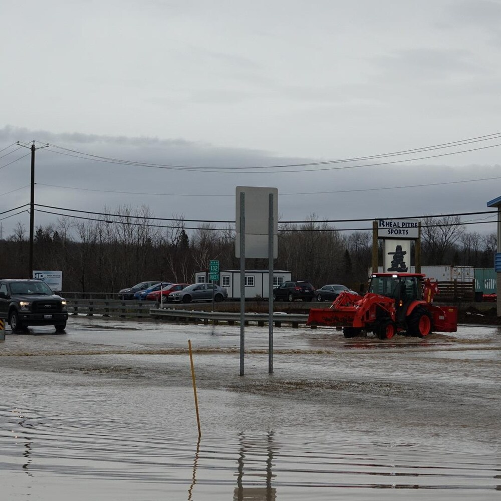 Un tracteur et une voiture circulent sur la route inondée, le 2 décembre 2020.