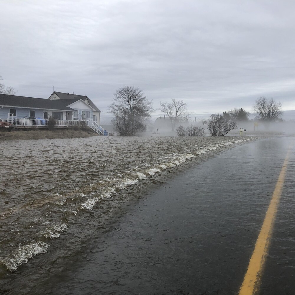 Rue inondée et vagues autour d'habitations.